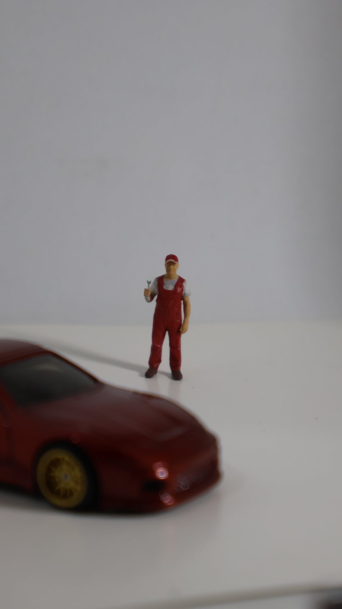 Figura mecánico miniatura 1:64 junto a auto die-cast para escala de referencia